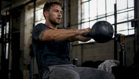 Young man swinging kettlebell in gym-streetwear