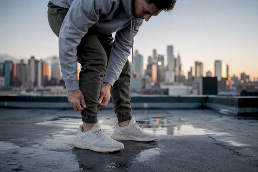 Man adjusting tapered joggers ankle outdoors