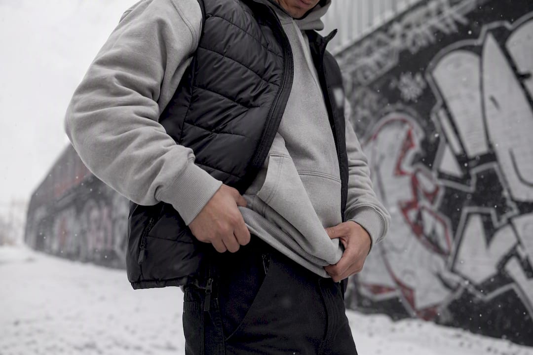 Person layering hoodie under parka outdoors