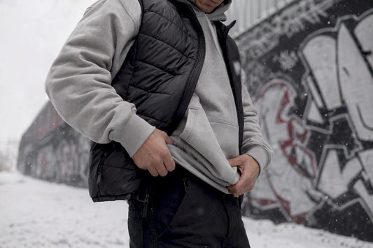 Person layering hoodie under parka outdoors