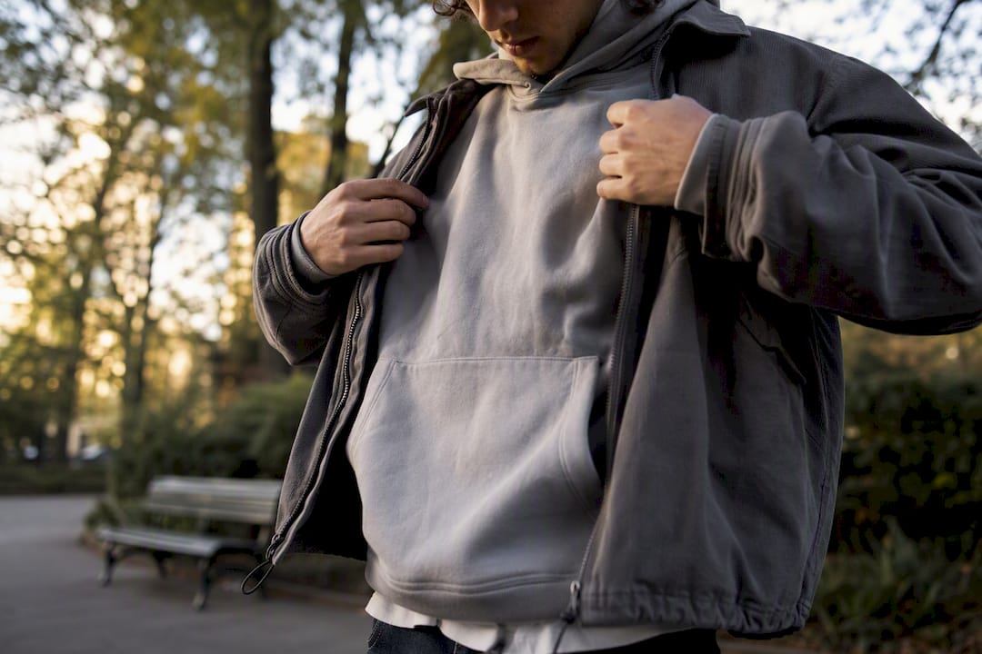 Streetwear layered outfit adjusting hoodie and jacket