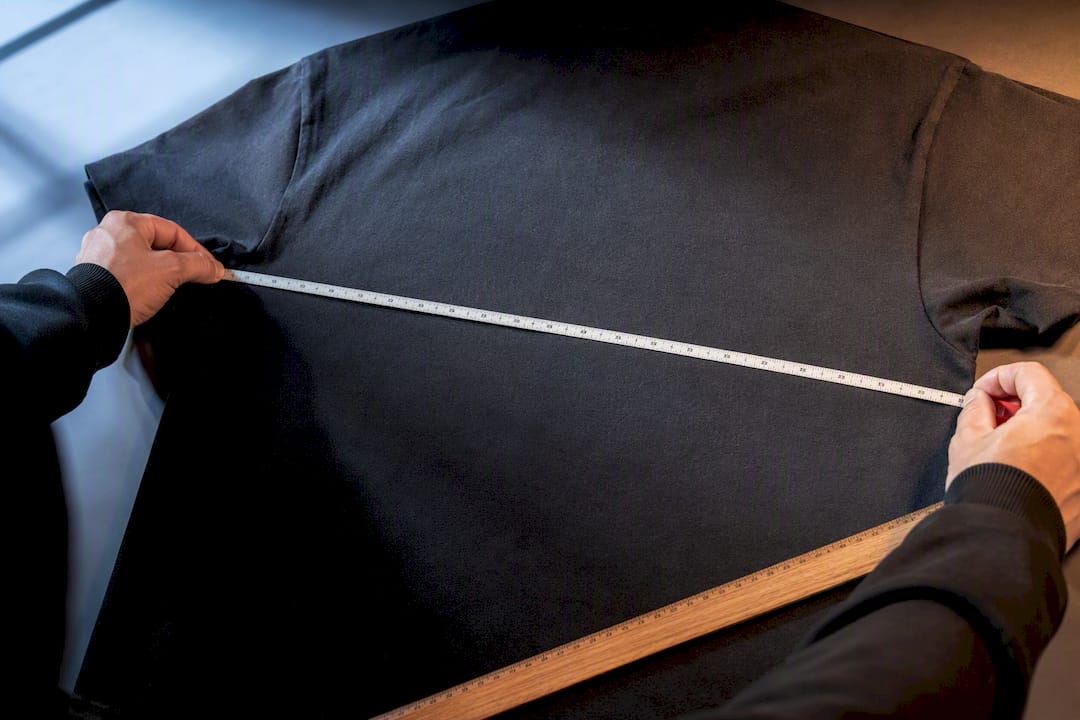 Hands measuring a heavyweight tee chest
