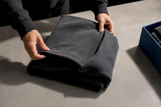 Hands folding a heavyweight hoodie into thirds