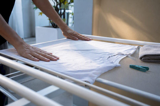 Damp cotton tee drying flat on rack